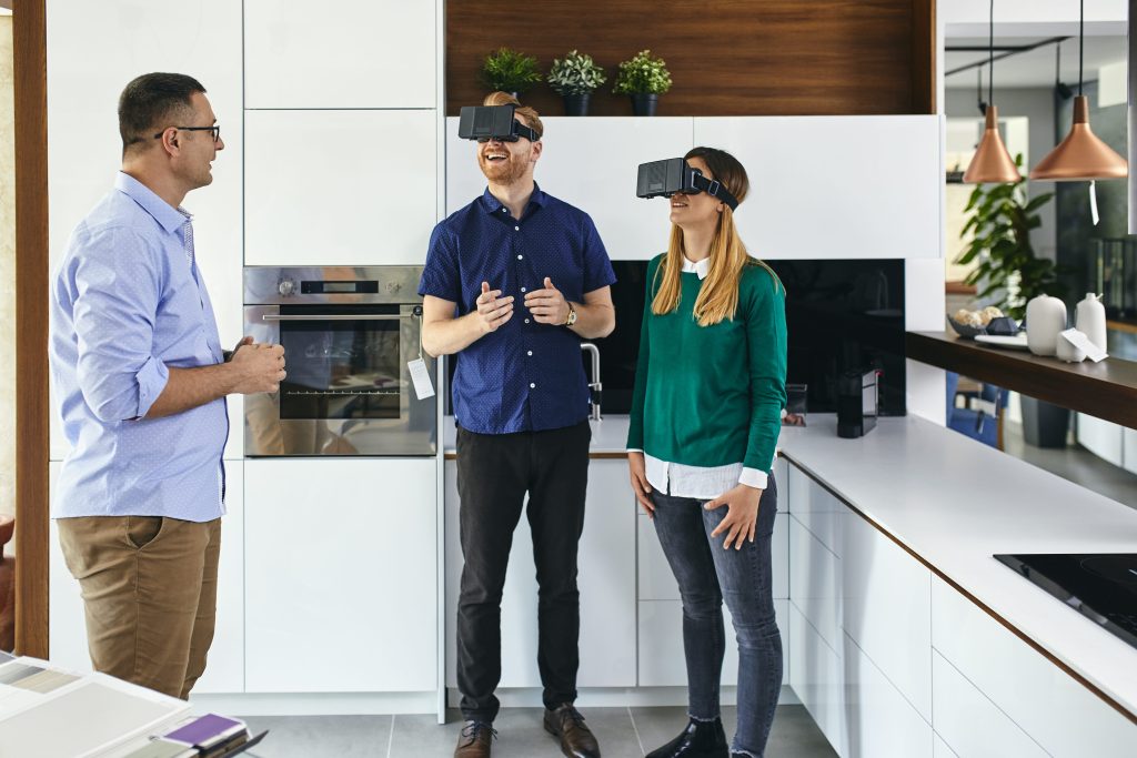 A real estate agent and a couple with VR glasses in a kitchen