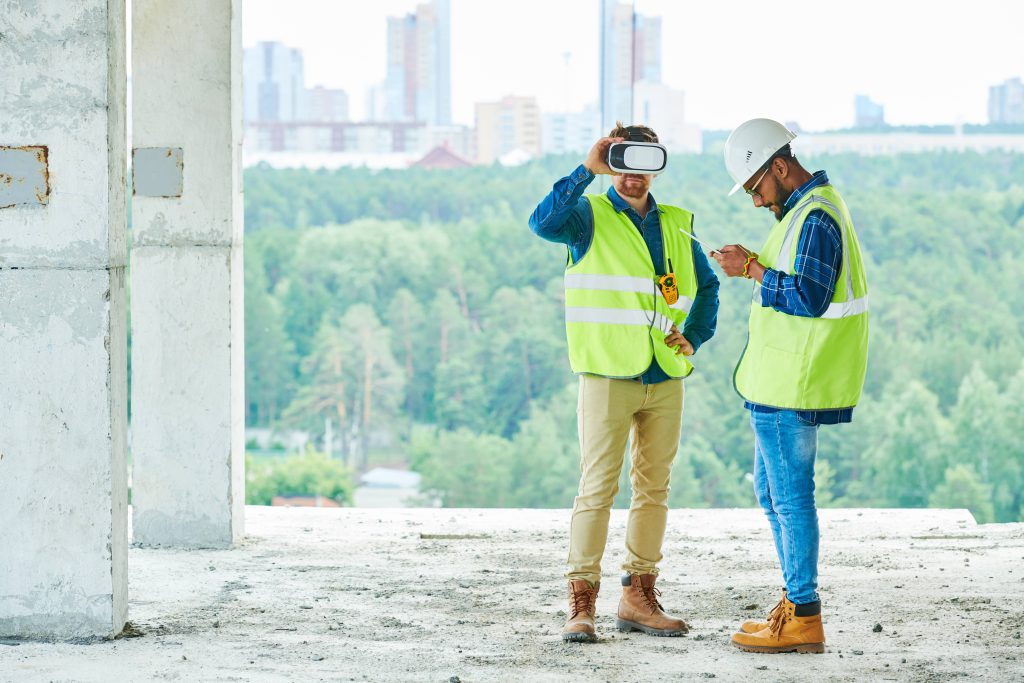Two construction workers in the construction site using a pair of VR glasses